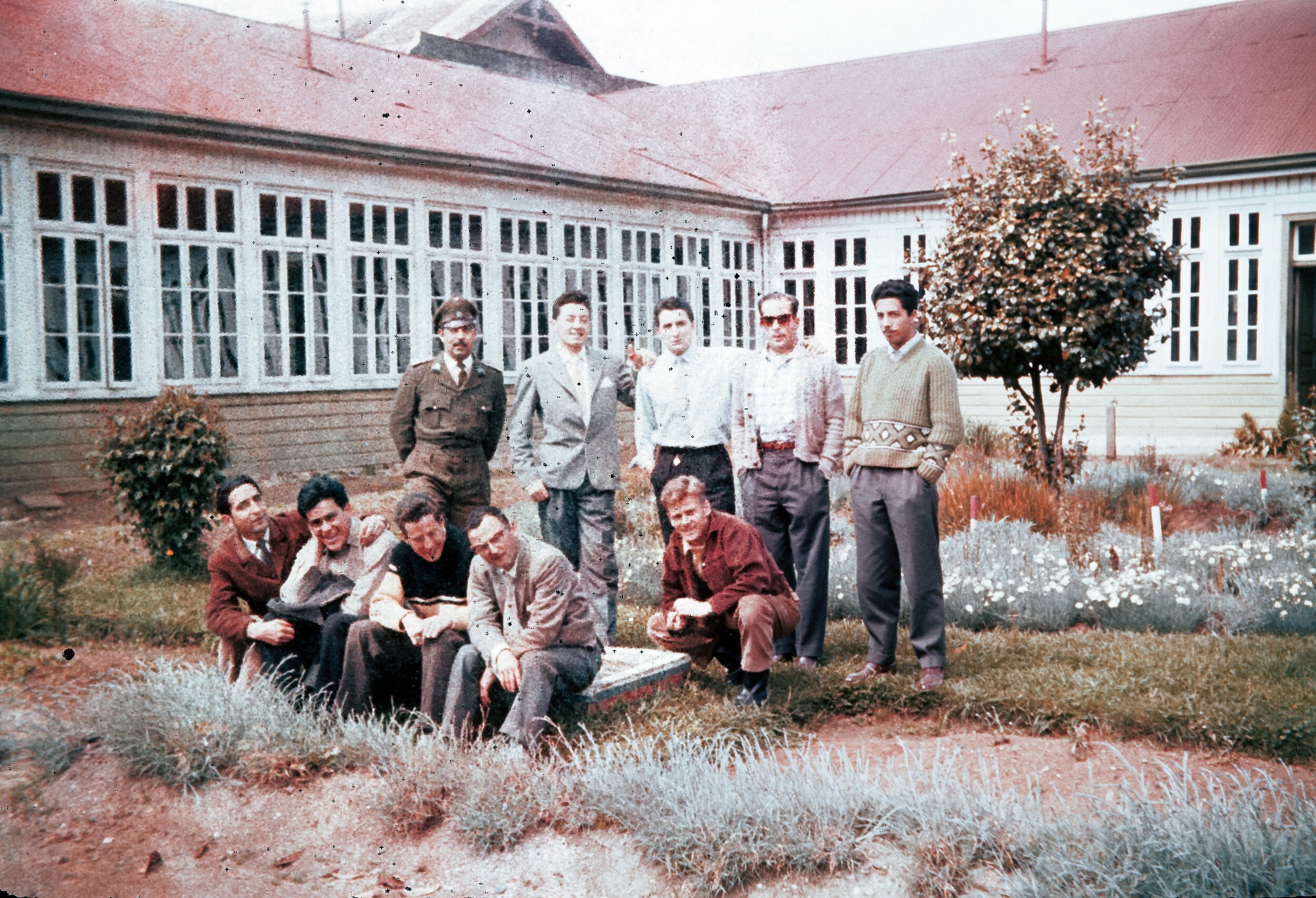 Retrato de plano entero de un grupo de Hombres junto a un carabinero afuera de la tercera comisaría de Carabineros