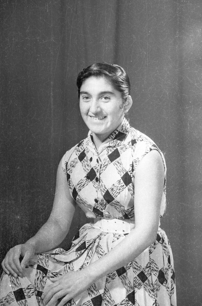 Retrato de estudio Plano americano de Mujer sentada de Medio perfil con manos en las rodillas mirando de frente
