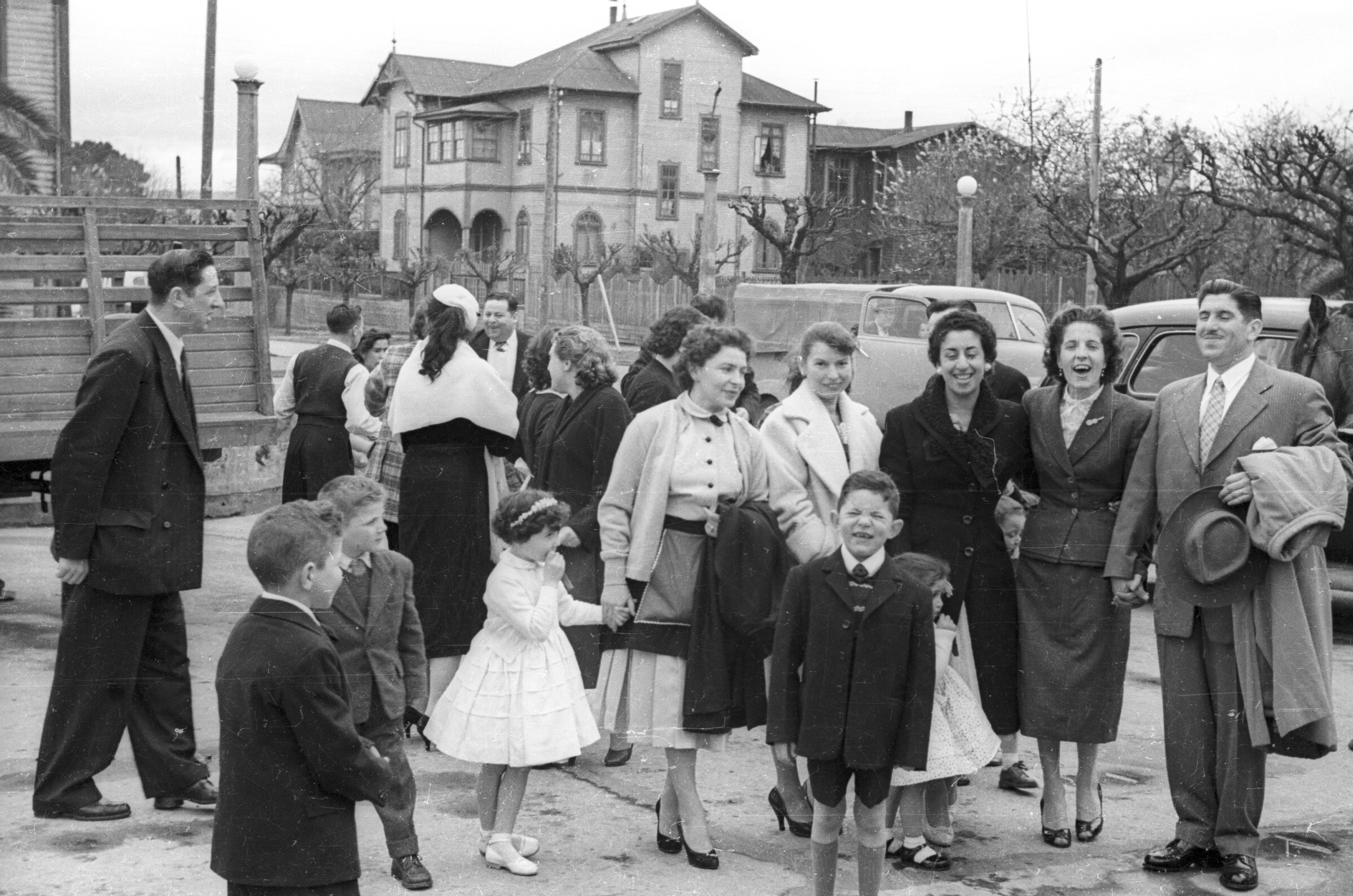 plano general de un grupo de Mujeres, Hombres, nos y una niña parados en la calle mientras sonríen. Todos visten formalmente ya que asistieron a un matrimonio. Lugar no identificado