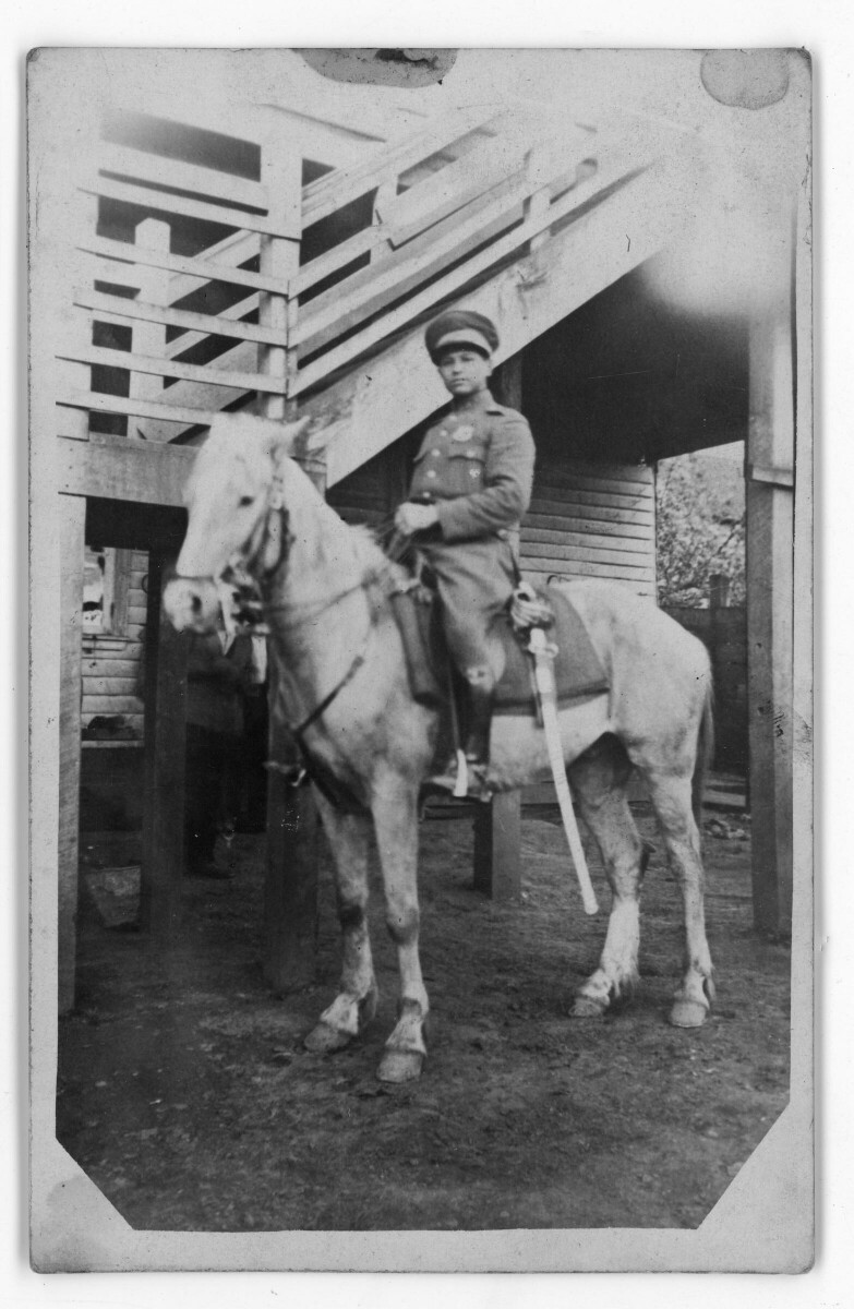 Retrato de plano entero de un carabinero posando montado en su caballo en las afueras de una estructura de madera