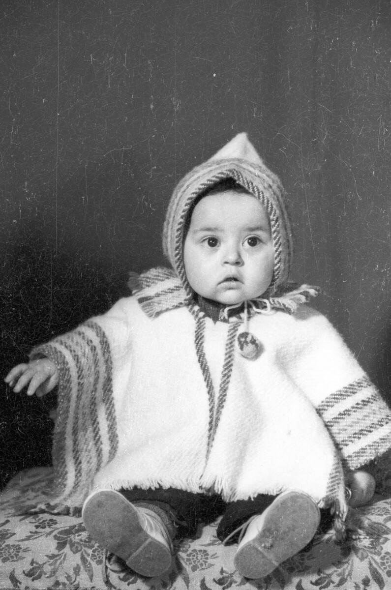 Retrato de estudio de Plano entero de un bebé con un poncho, posando sentado