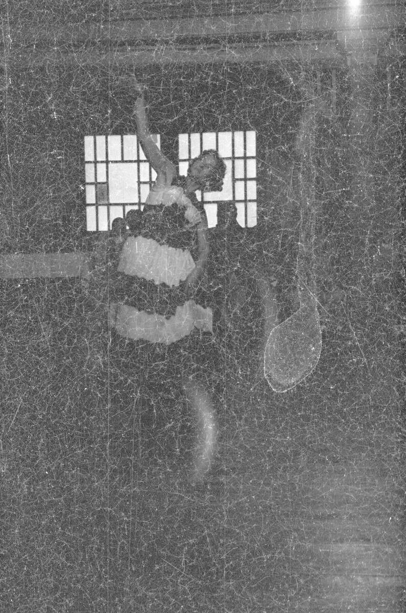 Plano entero de una mujer con Vestido realizando una presentación artística. Se encuentra en una estructura no identificada.