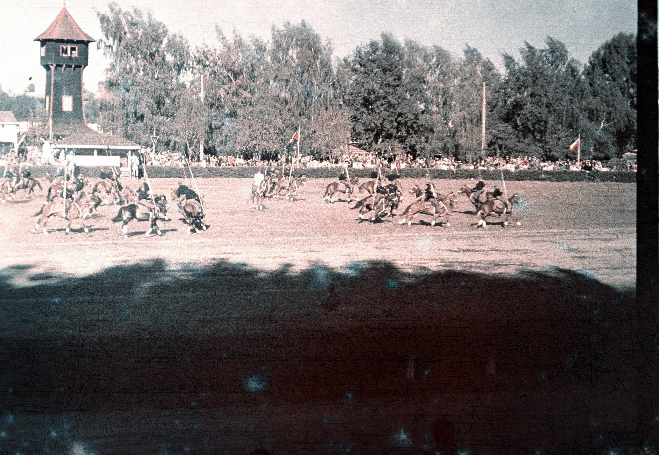 Plano general de un grupo de hombres uniformados a caballo portando banderines visto desde el sector de las gradas