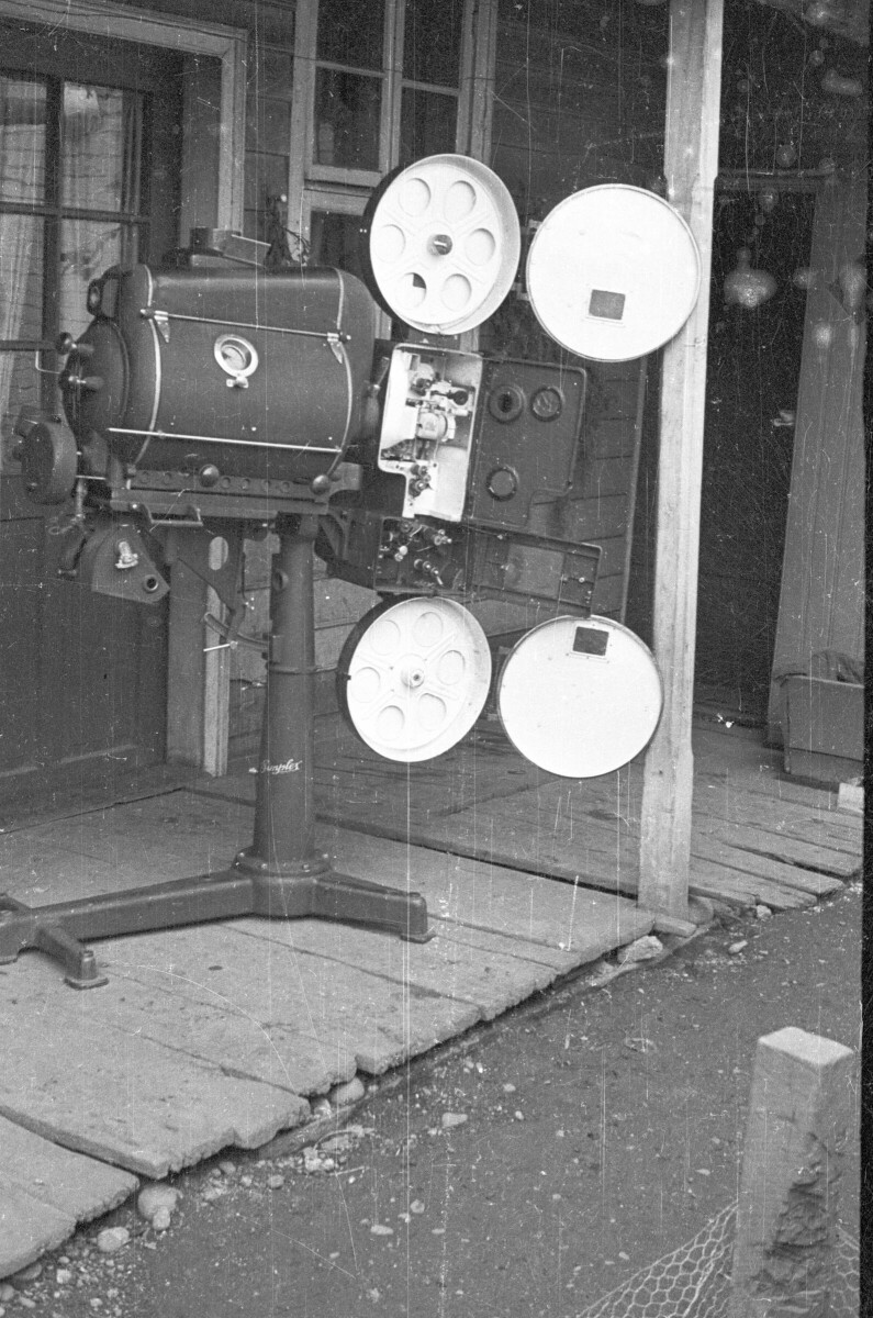 plano general de un proyector cinematográfico con una de sus partes abiertas, en las afueras de una casa