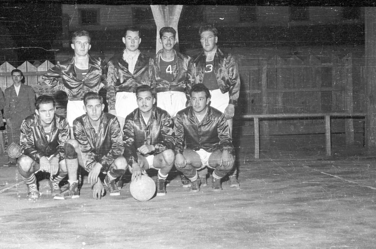 Plano entero de equipo de baloncesto masculino posando junto a su balón
