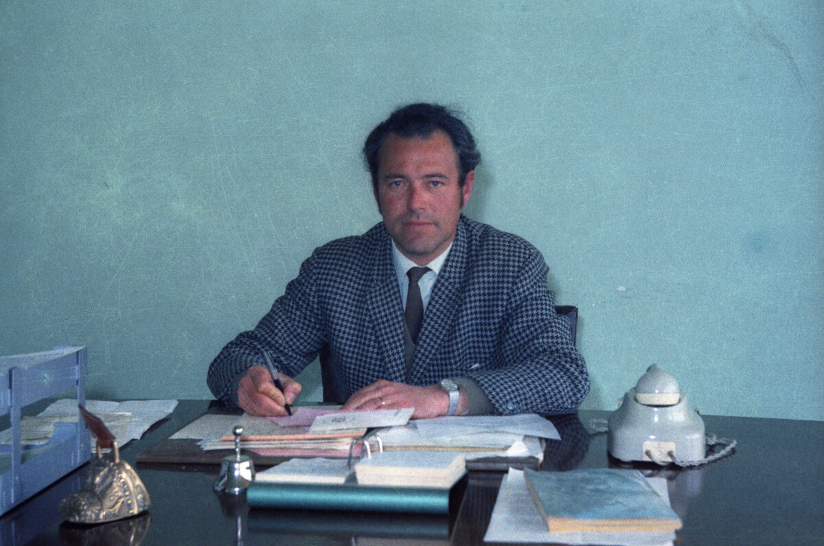 Plano medio de Enrique Larre sentado en un escritorio realizando anotaciones