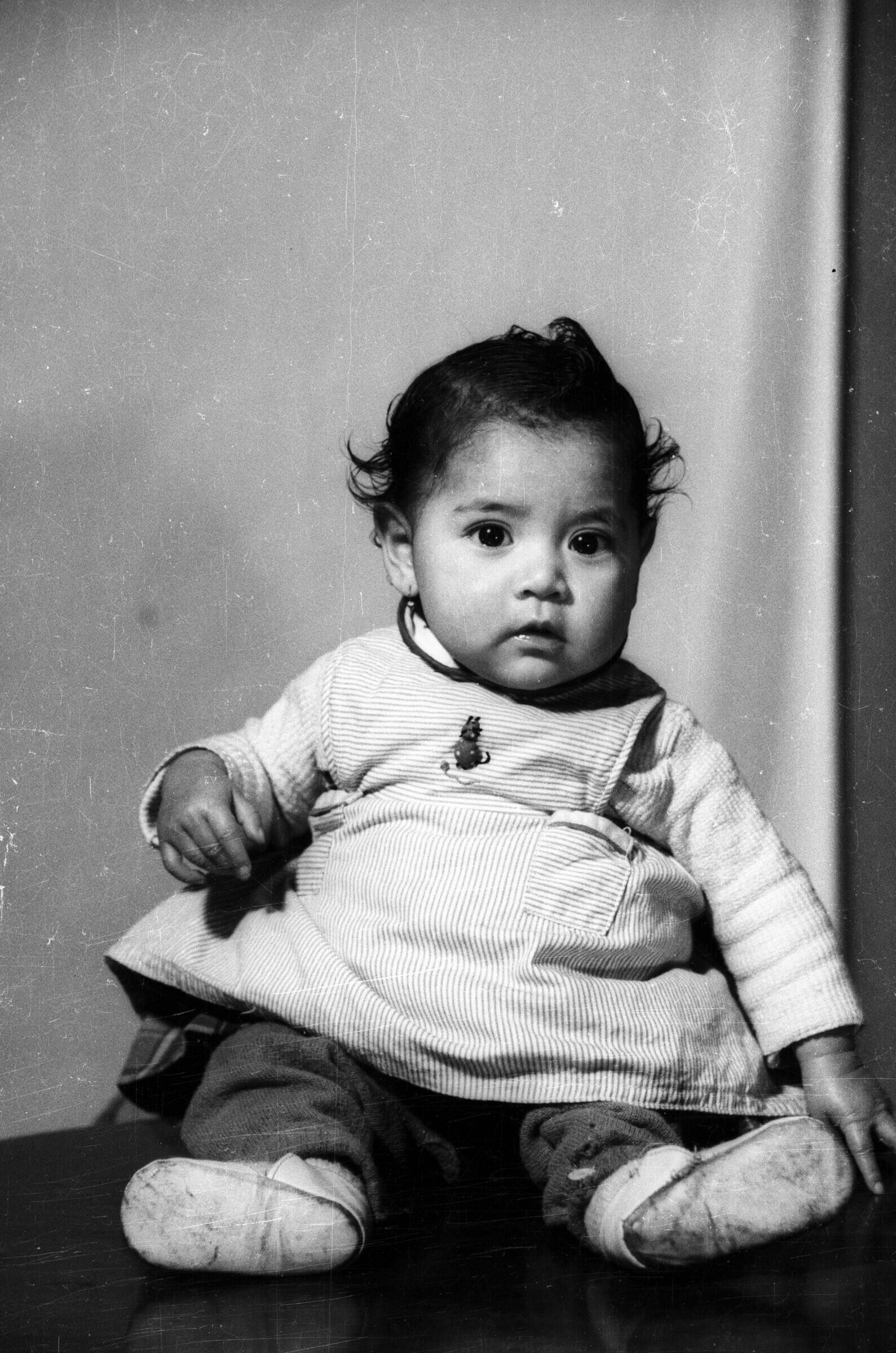 Retrato de estudio de Plano entero de niña de temprana edad con Vestido sentada de frente