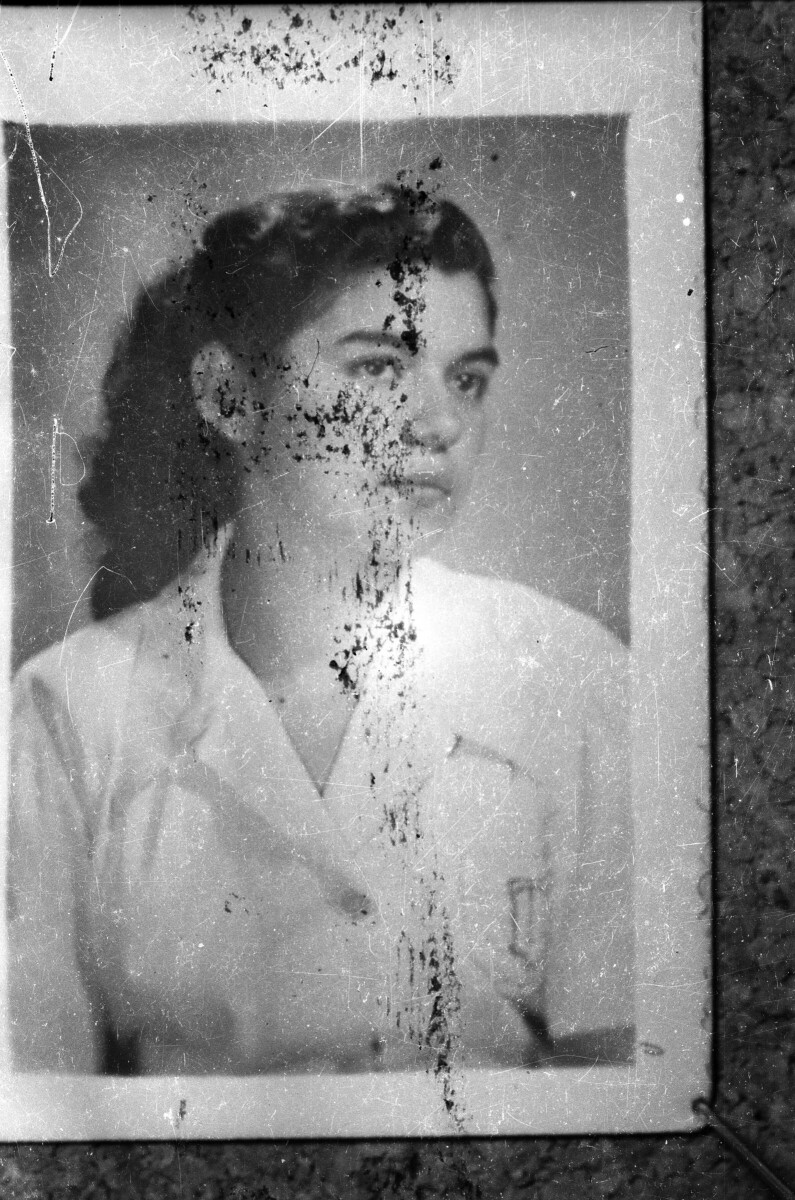 Plano entero de una fotografía corcheteada en una pared, con el Retrato de estudio de Plano medio de una mujer posando de Medio perfil