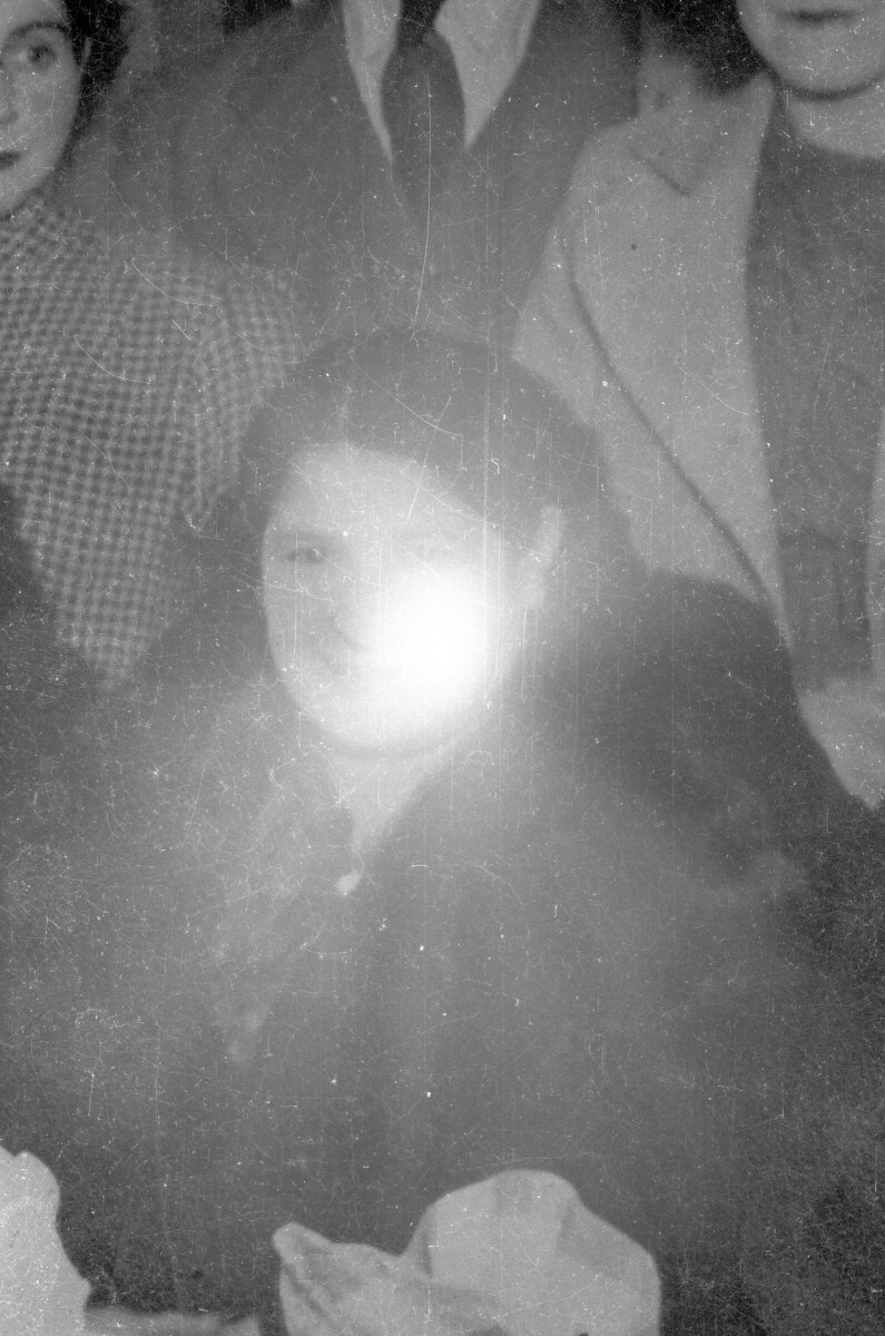 Retrato de plano medio de una mujer con abrigo posando entre un grupo de personas