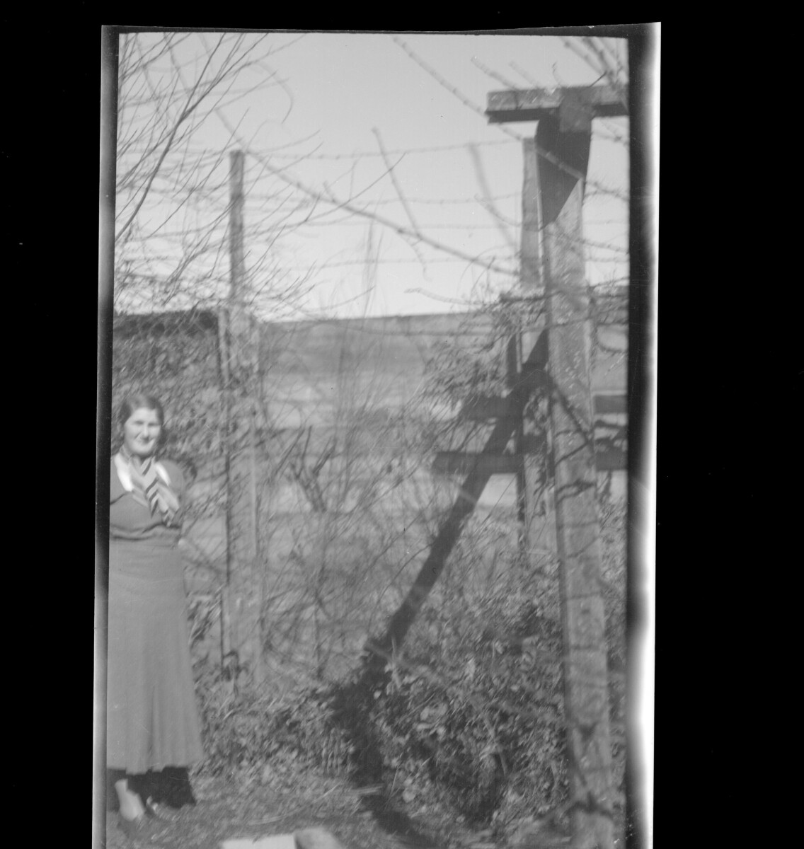 Retrato individual de una mujer con vestido en patio con un cerco detrás.