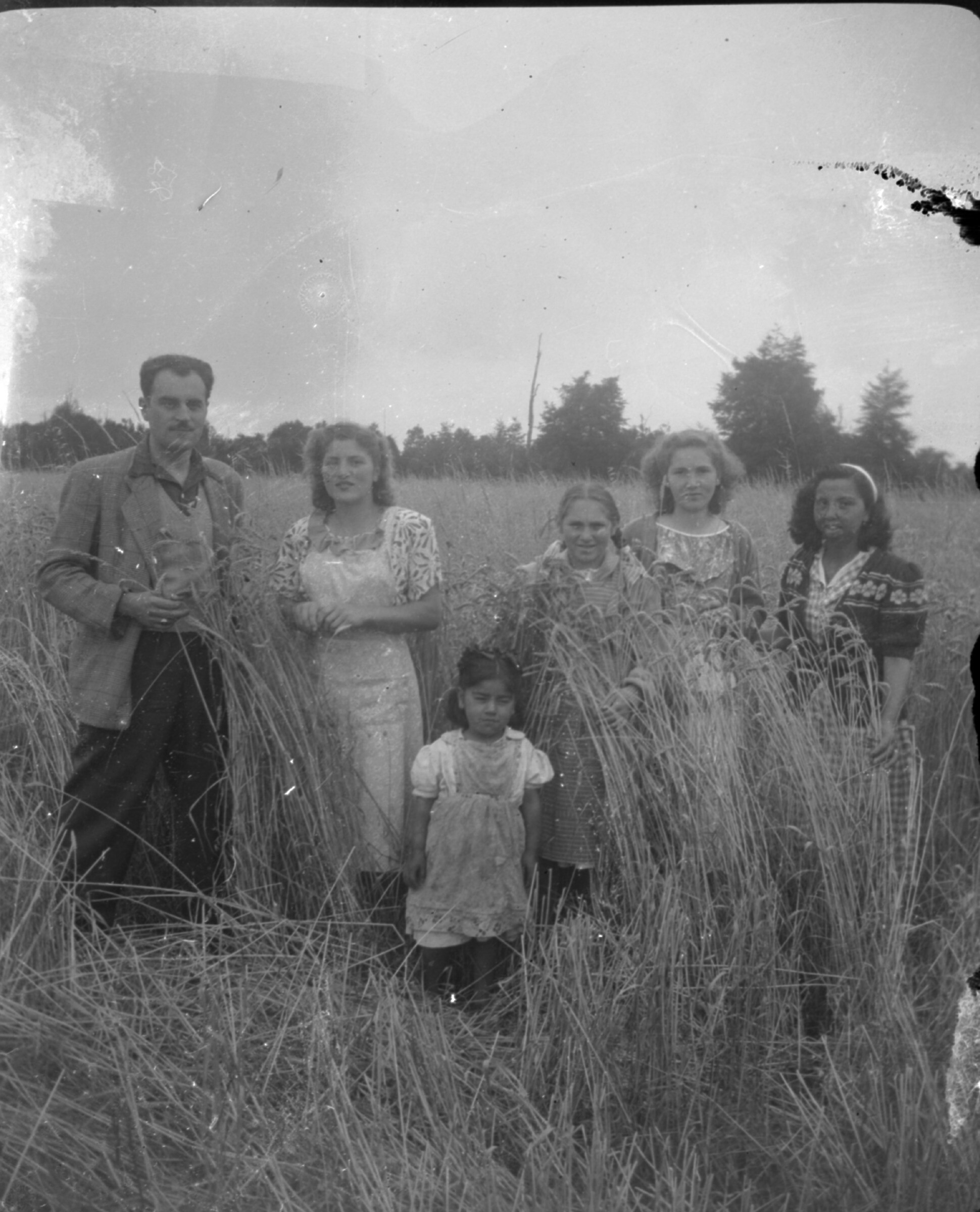 Plano entero de un grupo de personas posando de pie en un campo de trigo