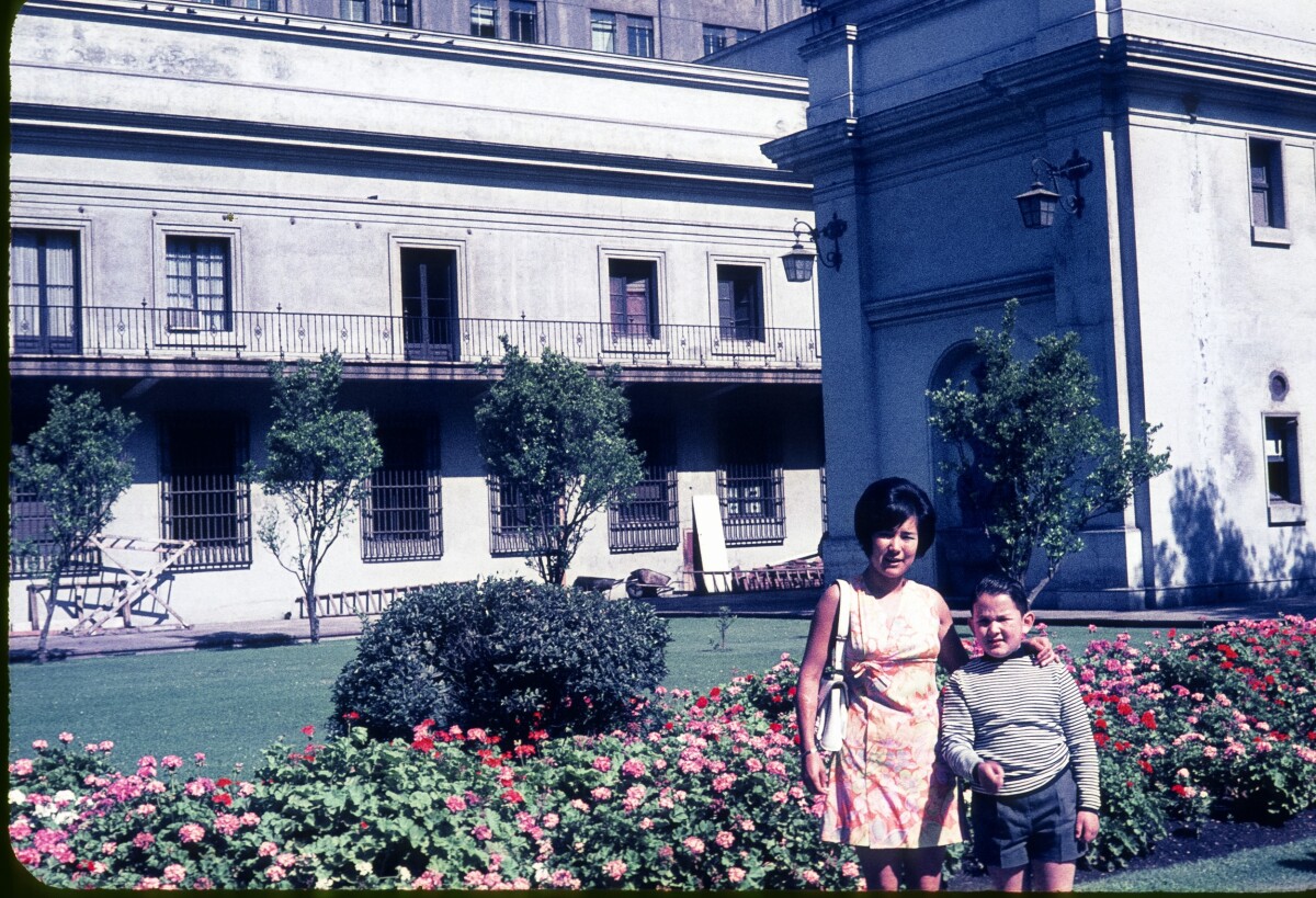 Retrato de plano medio de Mujer con Vestido y niño posando de pie en el patio de los Naranjos en el Palacio de la Moneda