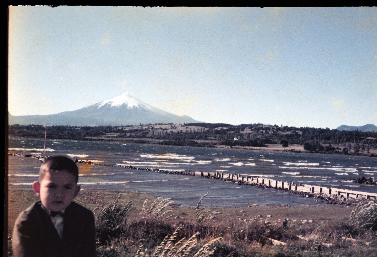 Retrato de plano medio de niño con Traje posando de frente junto al lago Villarica y volcán Villarica