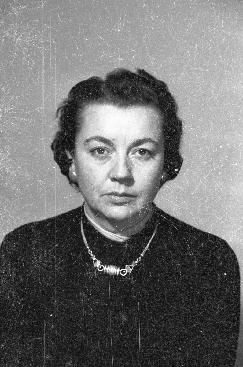 Retrato de estudio de Plano medio de una mujer posando de frente. Lleva puesto un collar, aros y tiene el pelo corto