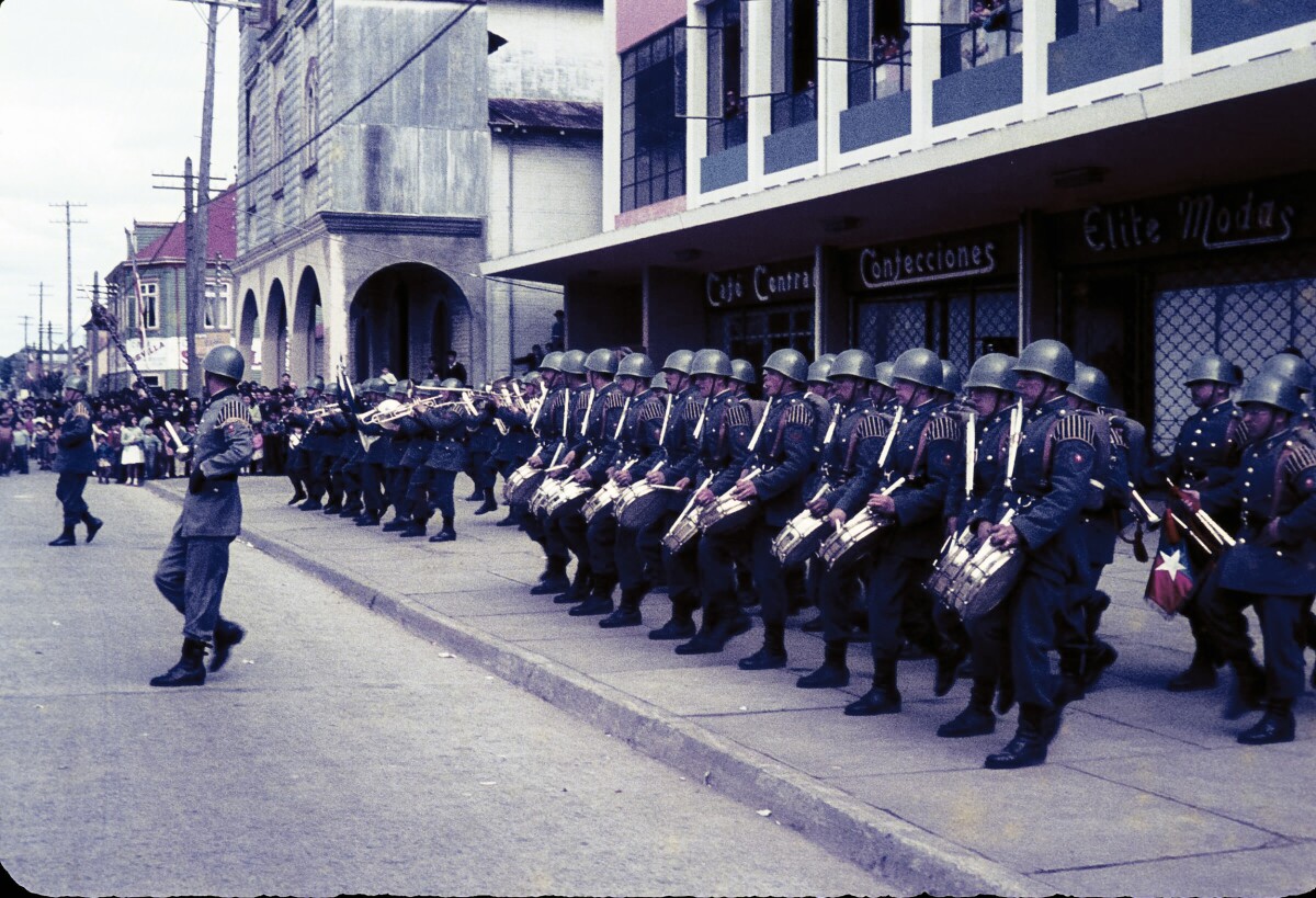 Plano entero de banda de guerra tocando para un desfile militar en calle Prat, frente a plaza de la Concordia de La Unión