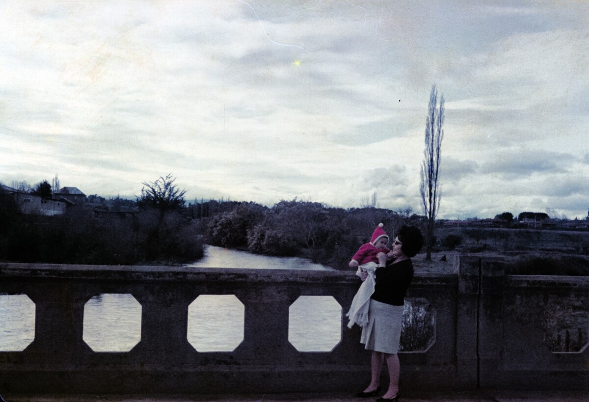 Retrato de plano entero de Mujer con Vestido y niña de temprana edad en brazos, de pie en puente Comercio de La Unión