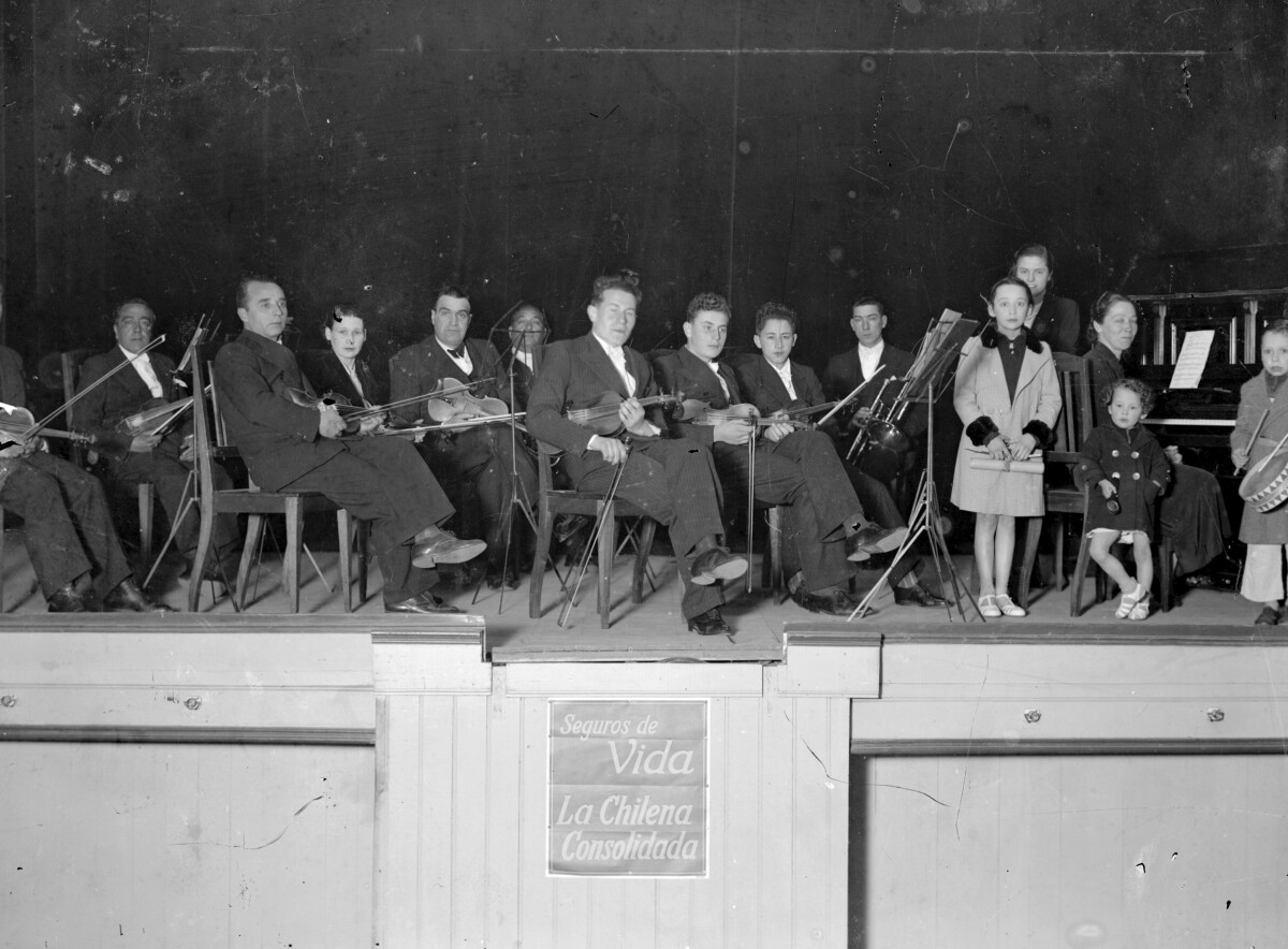 Plano general de un escenario con personas sosteniendo sus instrumentos musicales