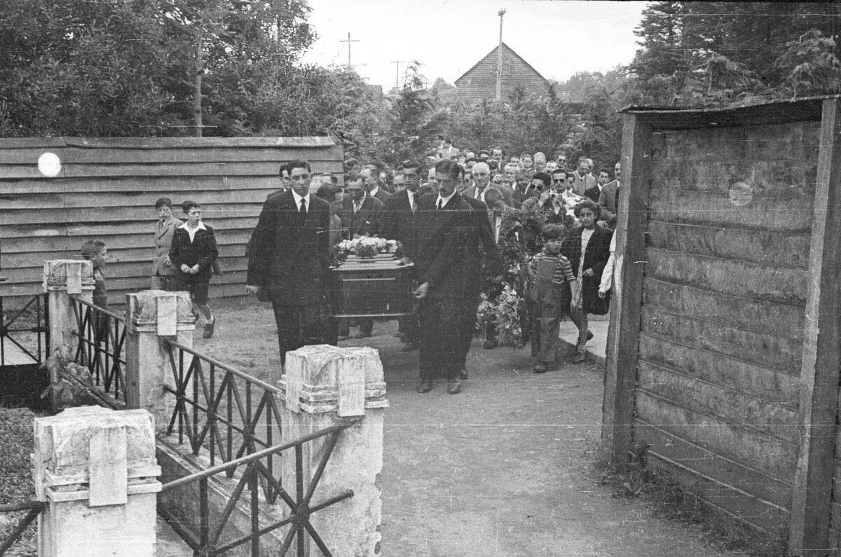 Plano general de grupo de hombres cargando un ataúd en el cortejo fúnebre