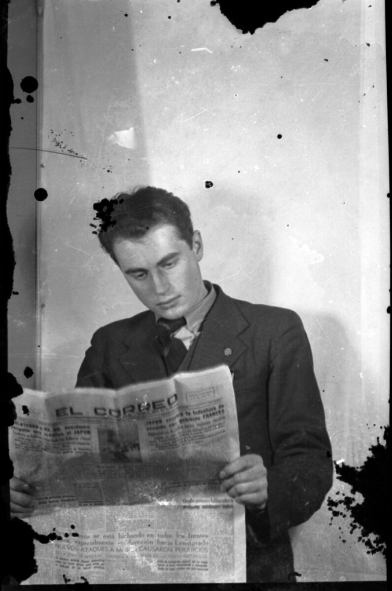 Plano medio de un hombre joven leyendo un diario en un estudio fotográfico