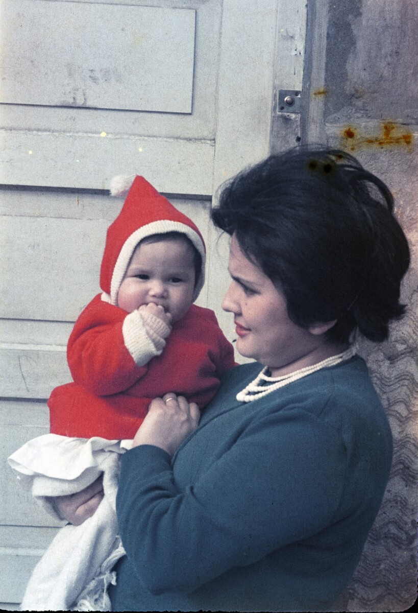 Retrato de plano medio de Mujer con Chaleco con un Bebé con Chaleco y gorro en brazos