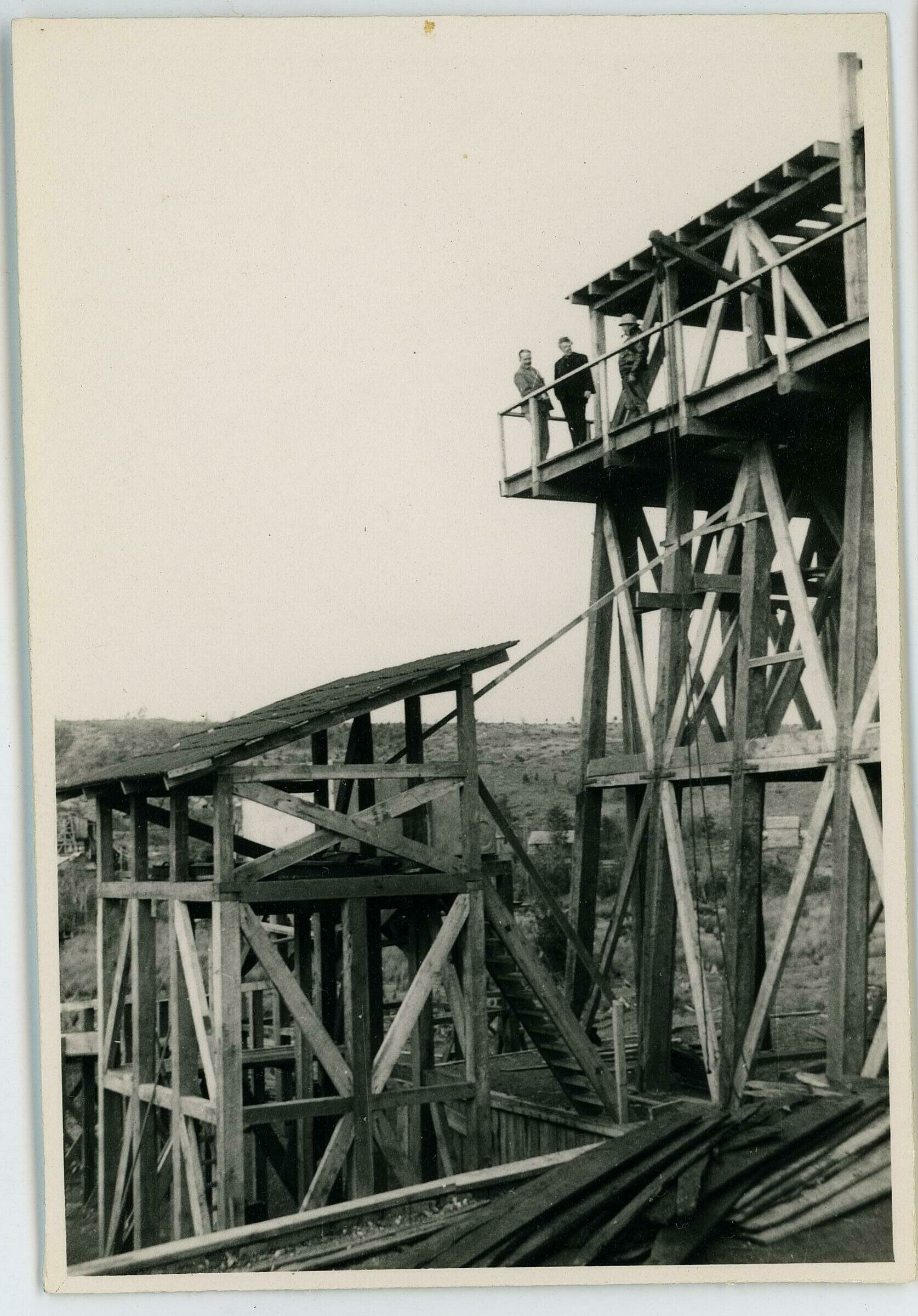 Plano entero de Olga Boettcher y dos hombres, parados en la parte alta de una estructura en construcción. Se encuentran de visita en la Compañía Carbonífera San Pedro de Catamutún