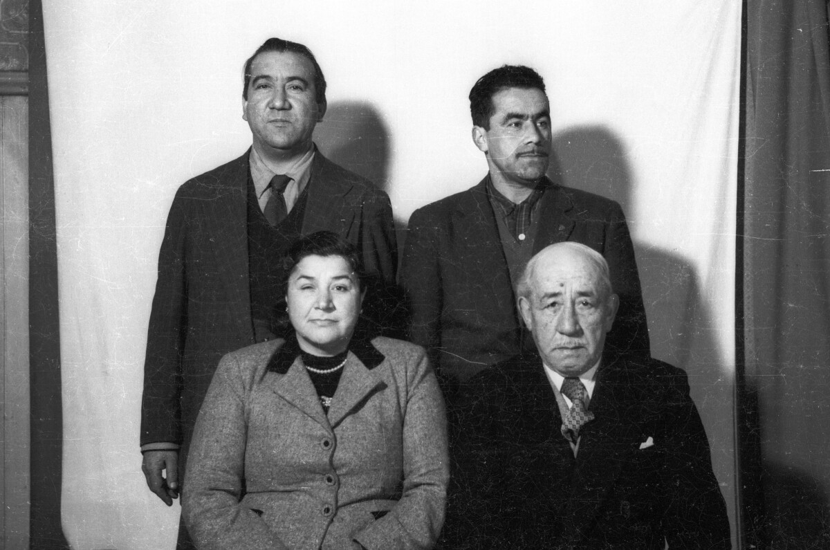 Retrato de estudio de Plano medio de una mujer con abrigo, un hombre adulto con Traje sentados y detrás de ellos dos hombres con Trajes de pie