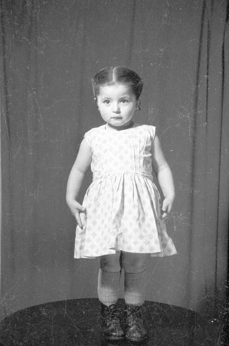 Retrato de estudio de Plano entero de niña con Vestido y bototos de pie encima de una mesa