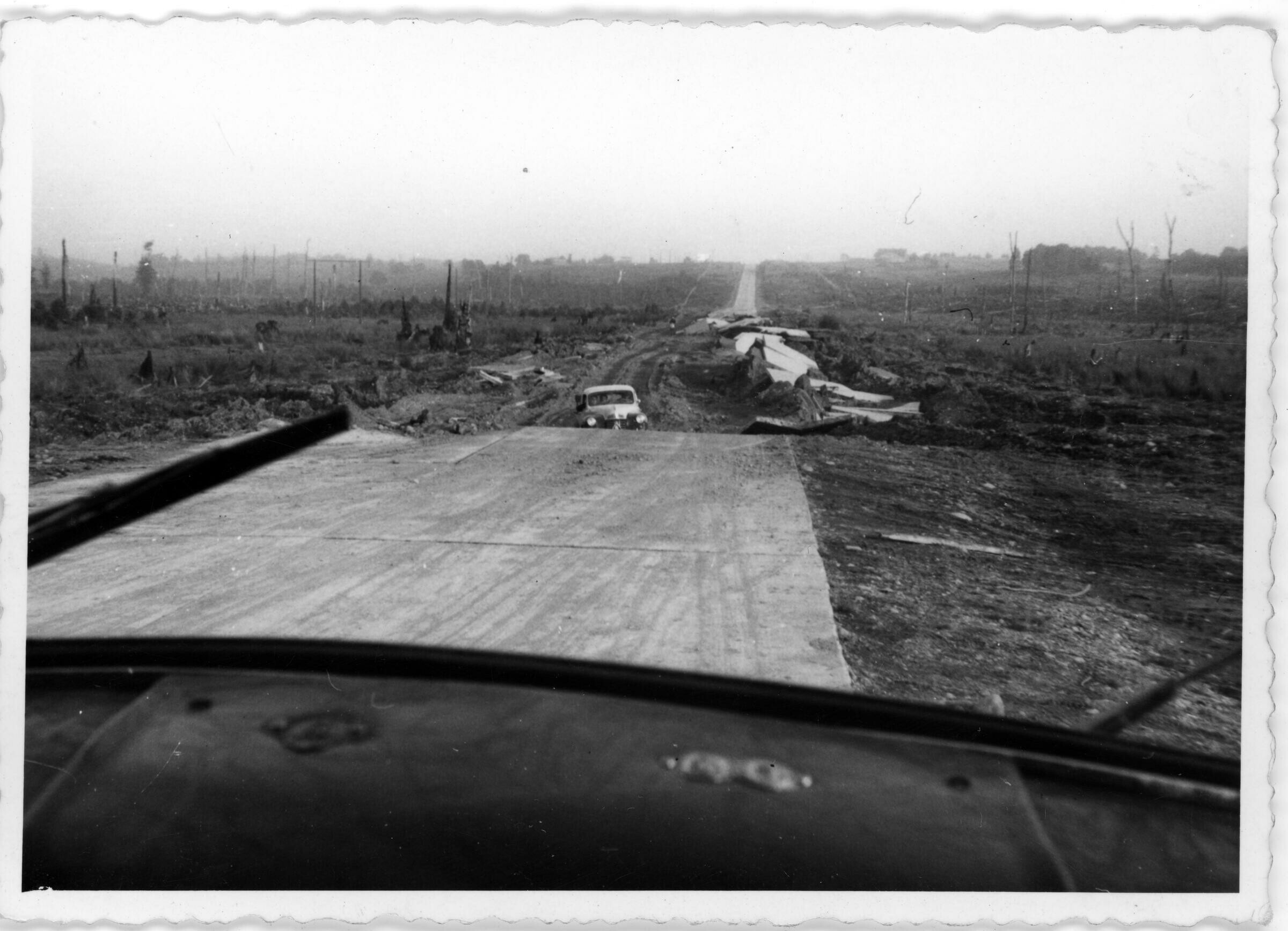 Plano general de un automóvil atrapado en una autopista de cemento dañada producto del terremoto de 1960. Camino hacia Puerto Montt.
