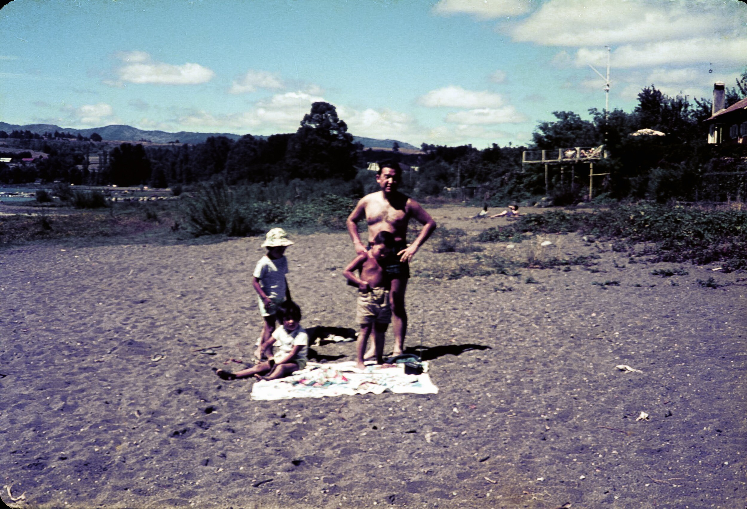 Retrato de plano entero de Hombre con Traje de baño junto a dos niñas y niño en una playa no identificada