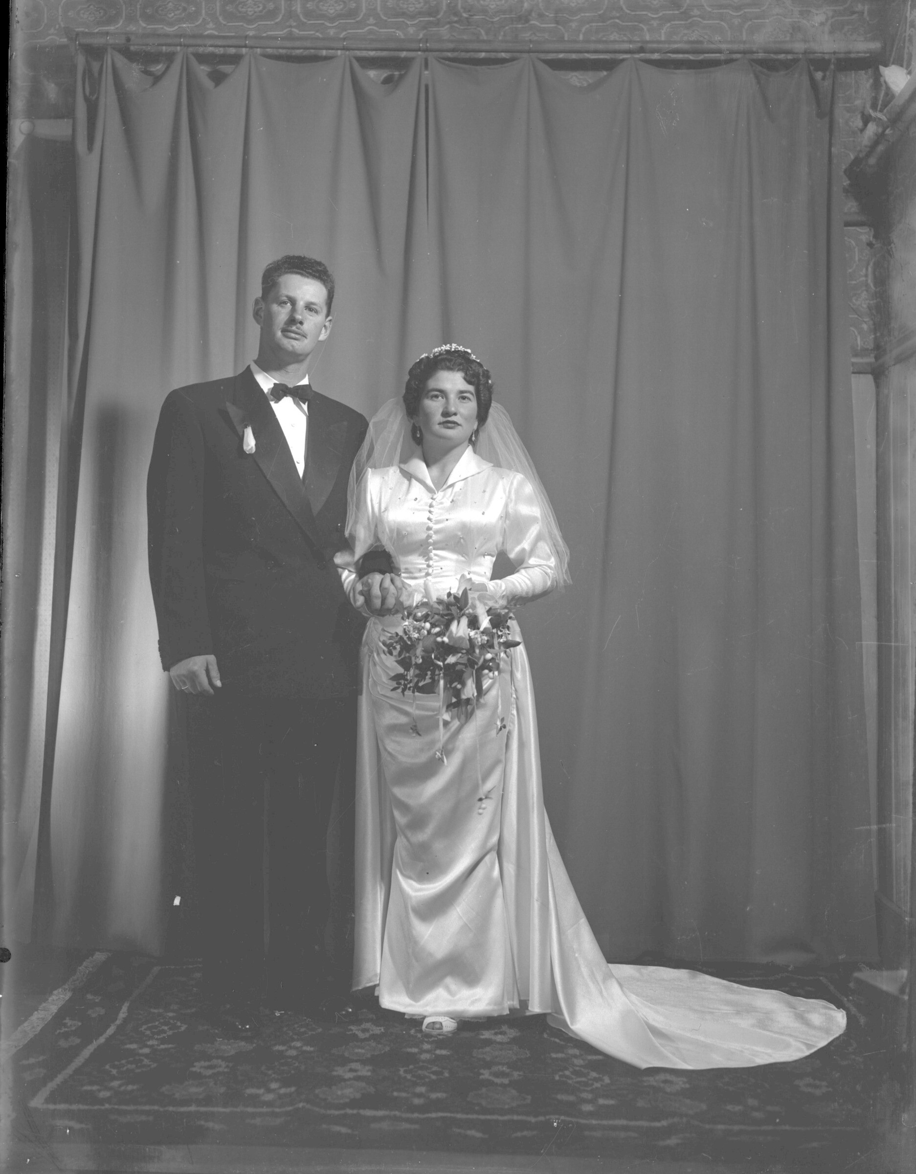 Retrato estudio plano entero de Yery Westermeier vestida de novia junto a Orlando Mohr, los dos de pie posando de frente