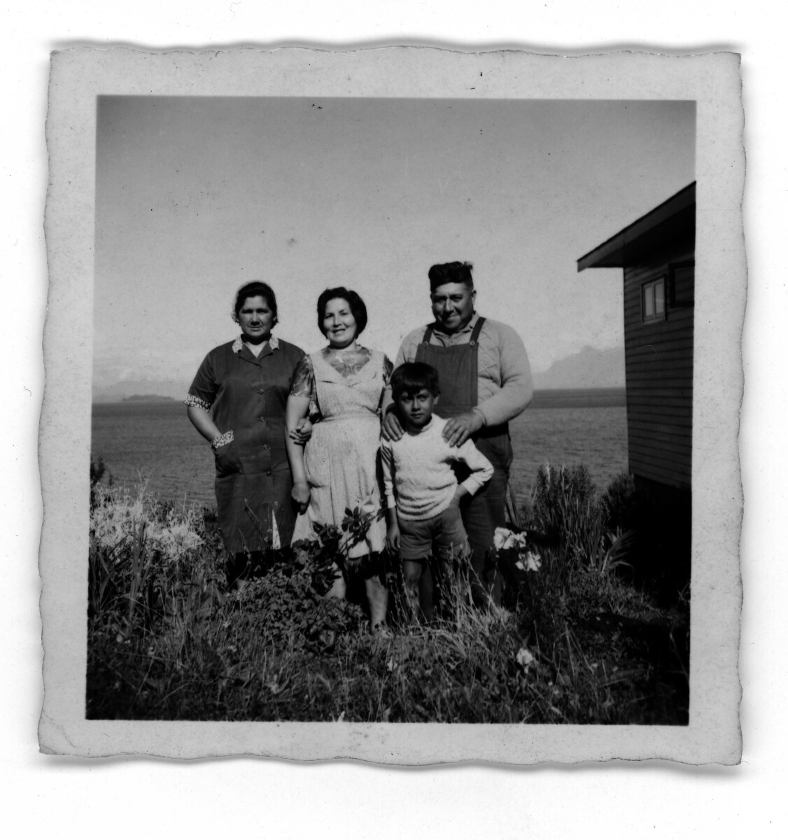 Retrato grupal de dos mujeres, un hombre y un niño junto a casa de campo a las orillas del Lago Ranco