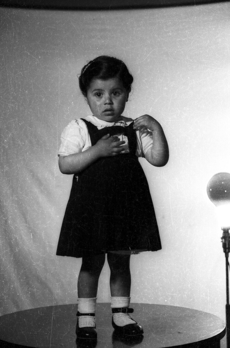 Retrato de estudio de Plano entero de una niña con Vestido, posando parada sobre una mesa
