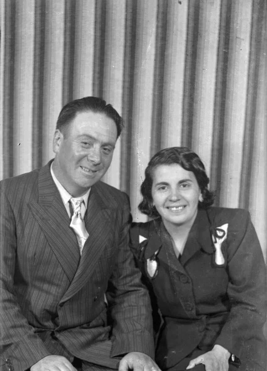 Plano medio de una pareja sonriendo y posando para el retrato en un estudio fotográfico