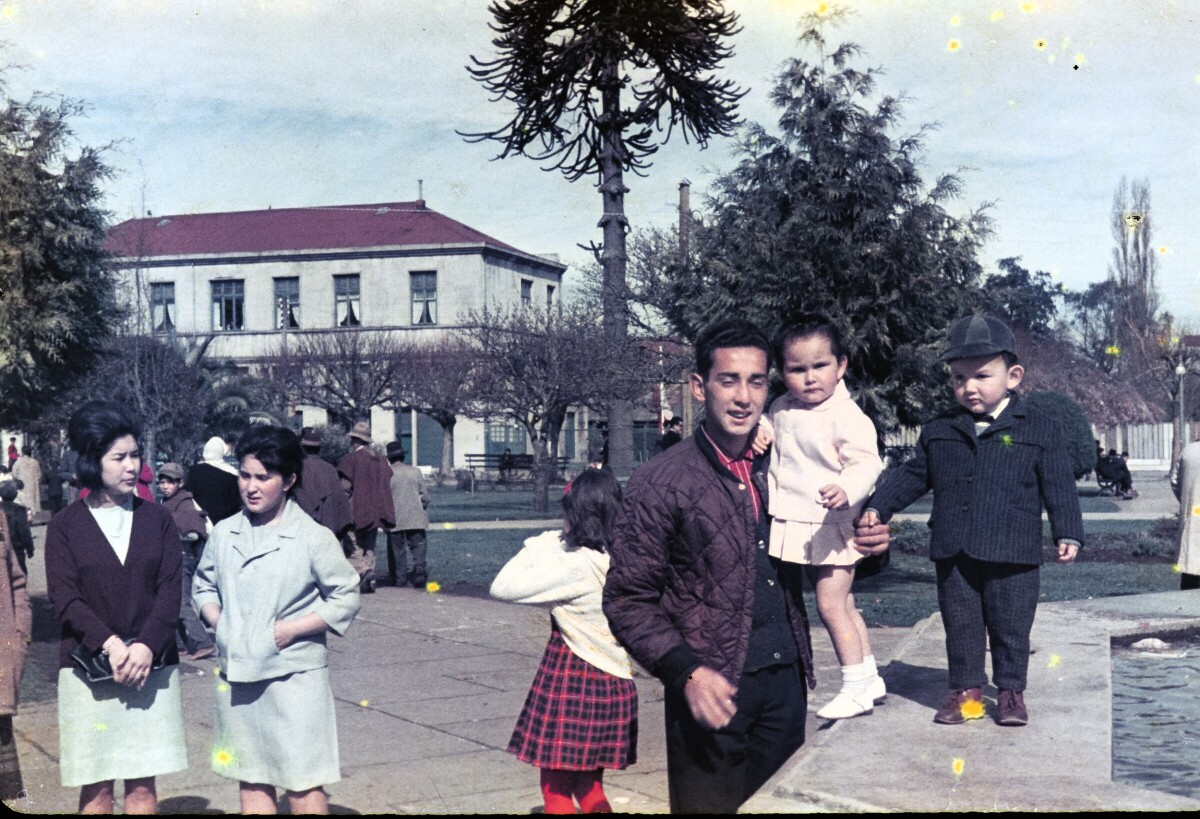 Retrato plano americano de Hombre con niña en brazos y niño de temprana edad de pie en pileta de agua en plaza de la Concordia de La Unión