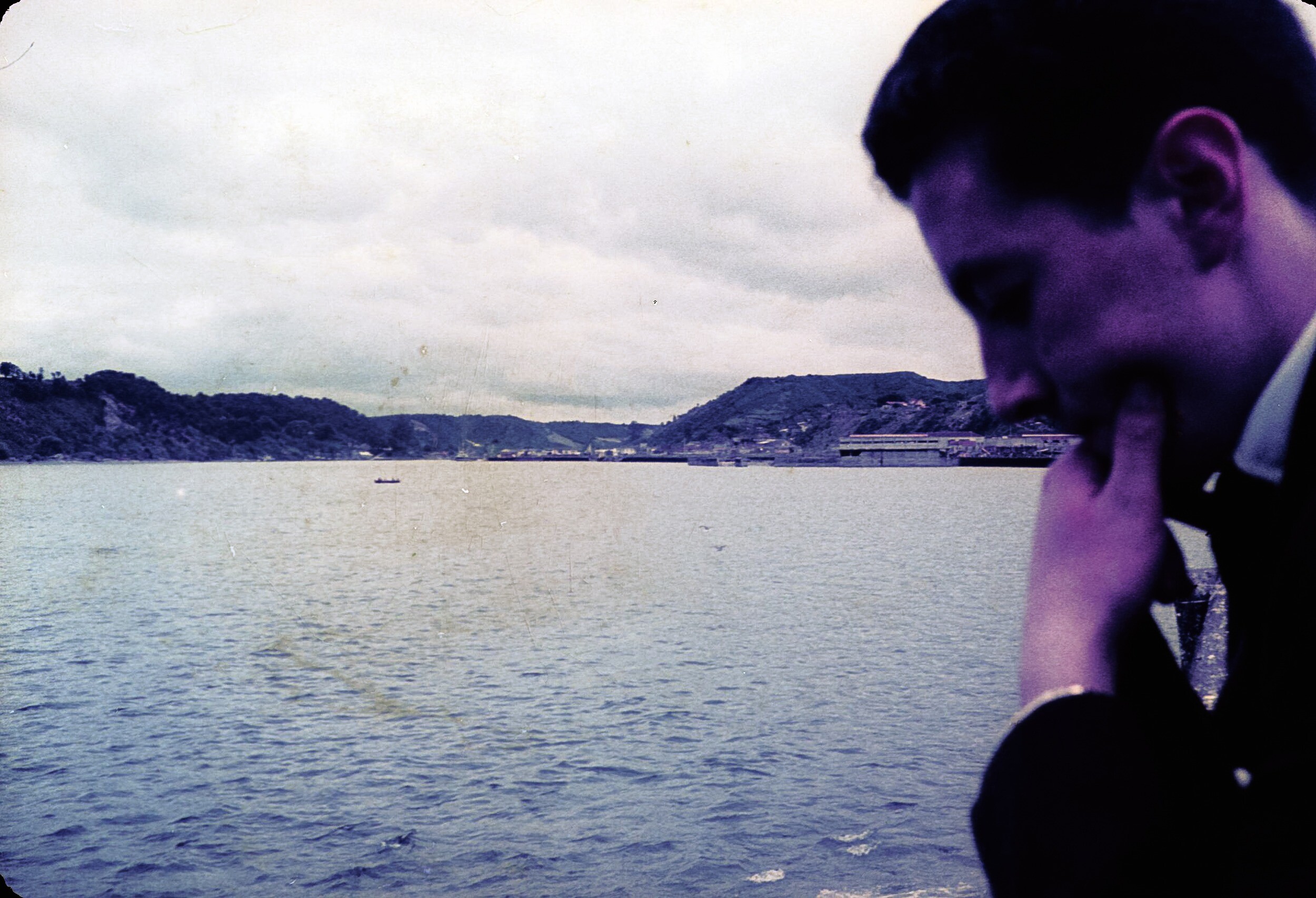 Retrato de plano medio de Hombre posando de frente con la mano en el mentón, de fondo la costanera de Puerto Montt