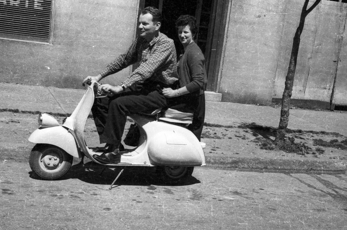 plano general de Gonzalo Carrasco y una mujer, paseando en una moto en el frontis del estudio fotográfico -Foto Real-