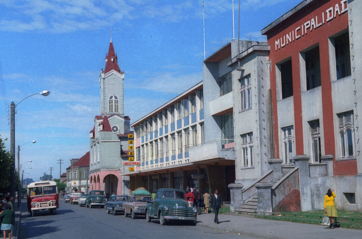 plano general de calle Prat. Se puede observar una fila de autos estacionados en el frontis de la municipalidad y también la parroquia San José en el fondo