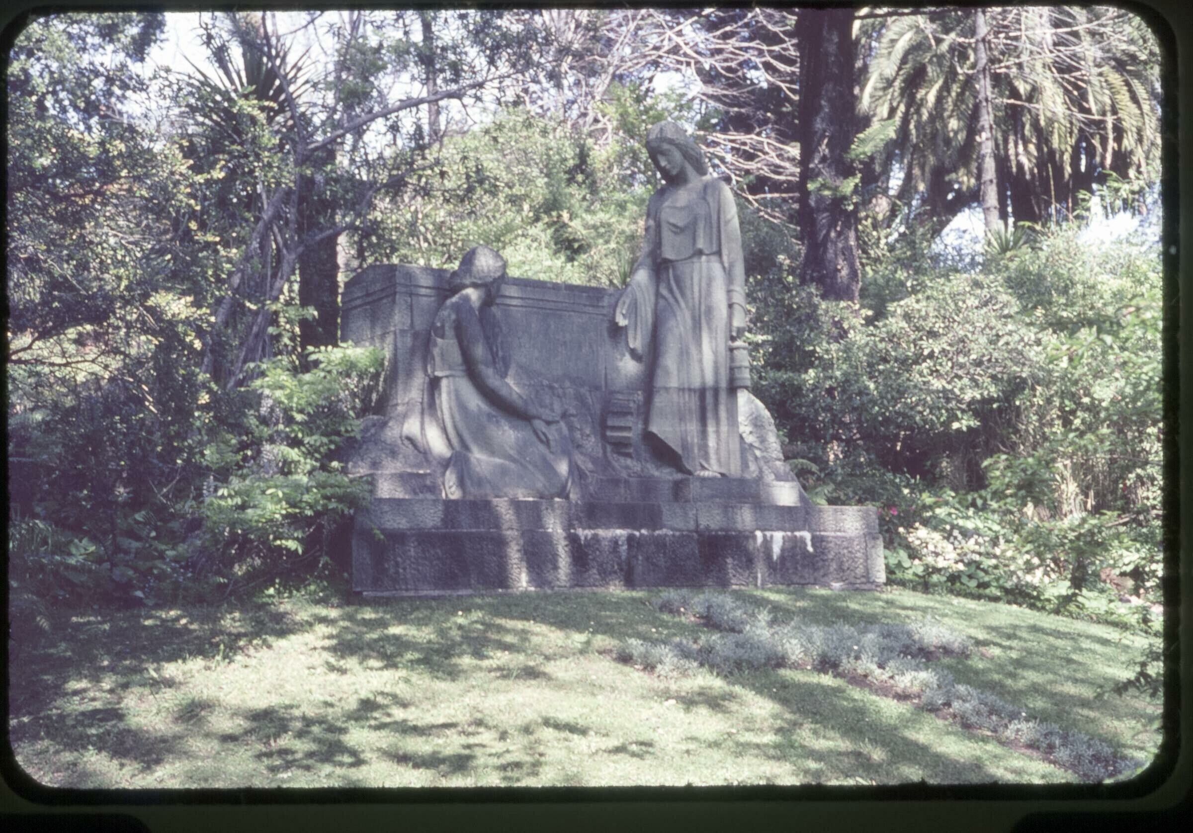 Plano entero de un monumento funerario con una cruz hecha con pasto en el suelo