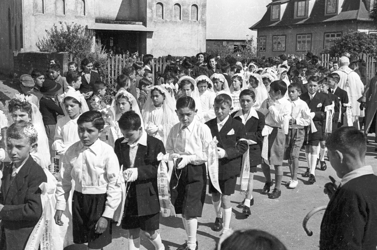 plano general de un grupos de Niñas y Niños formados en dos hileras. En el fondo un sacerdote está parado esperando que salgan todos de la parroquia inmaculada concepción.