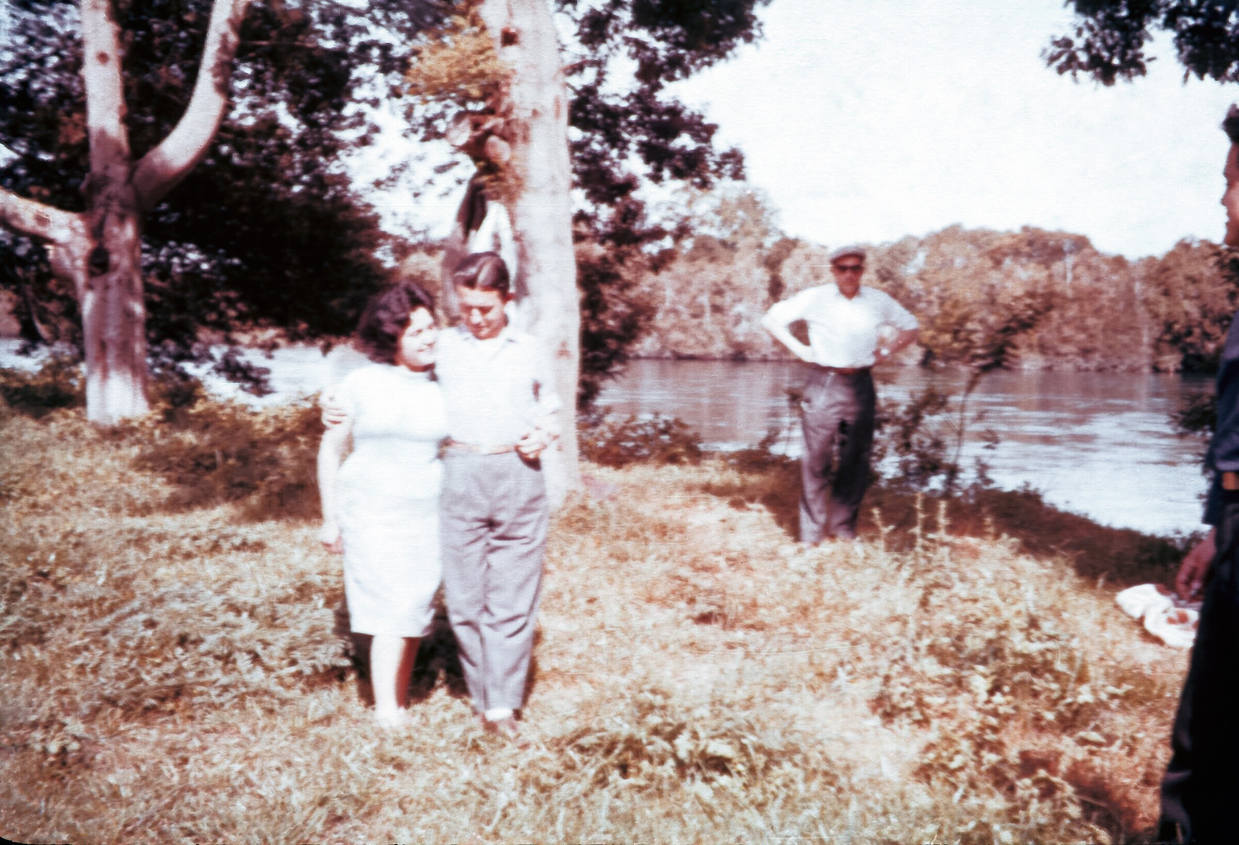 Retrato de plano entero de Hombre abrazado de Mujer en un prado al lado de un río