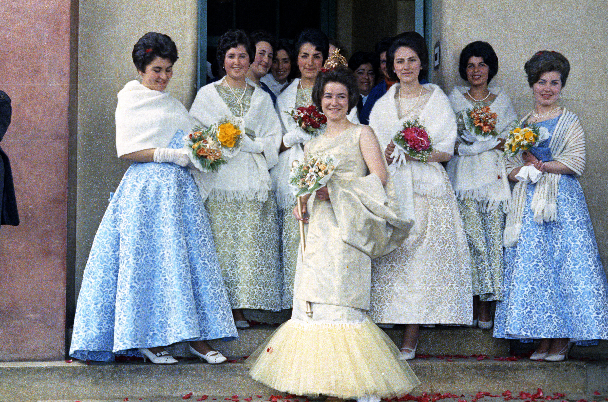 Retrato de plano entero de un grupo de Mujeres, entre ellas se encuentra Nora Manzano, Domínica Carrasco y Loreta Ferrón, posando de frente con un ramo de flores en las manos. Se encuentran en la actual entrada de Urgencias del Hospital Juan Morey de La Unión