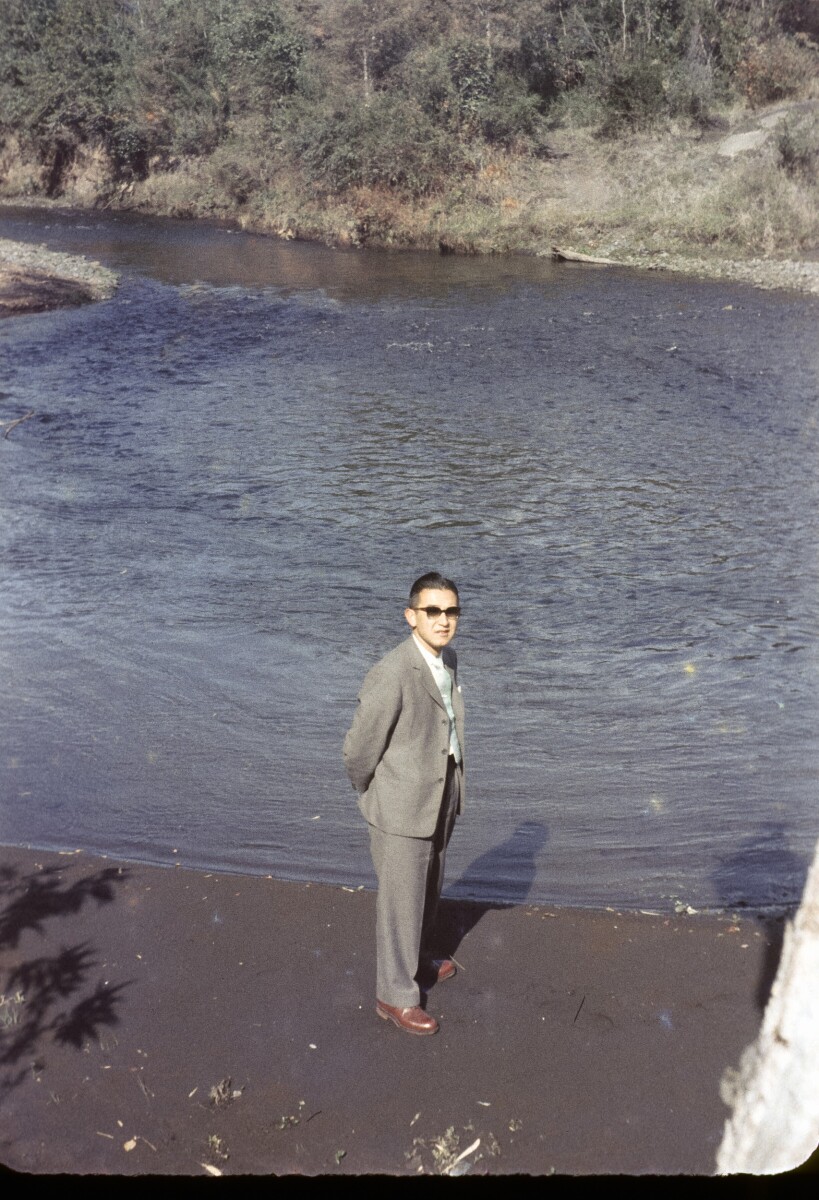 Vista superior Retrato de plano entero de Hombre con Traje a orillas de un río, que lo rodea un cerro poblado de árboles