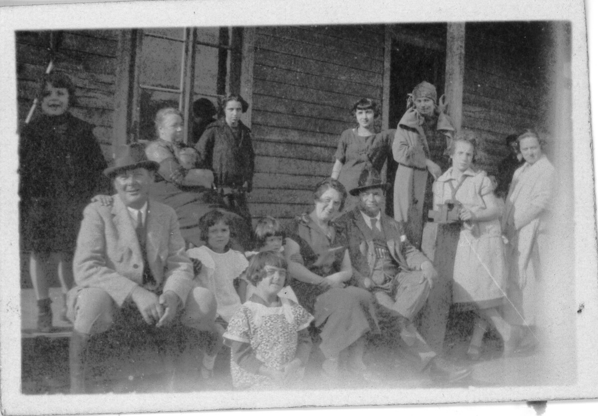 Retrato grupal de plano entero de Mujeres, Hombres y Niñas, posando en el pasillo frontal de una casa