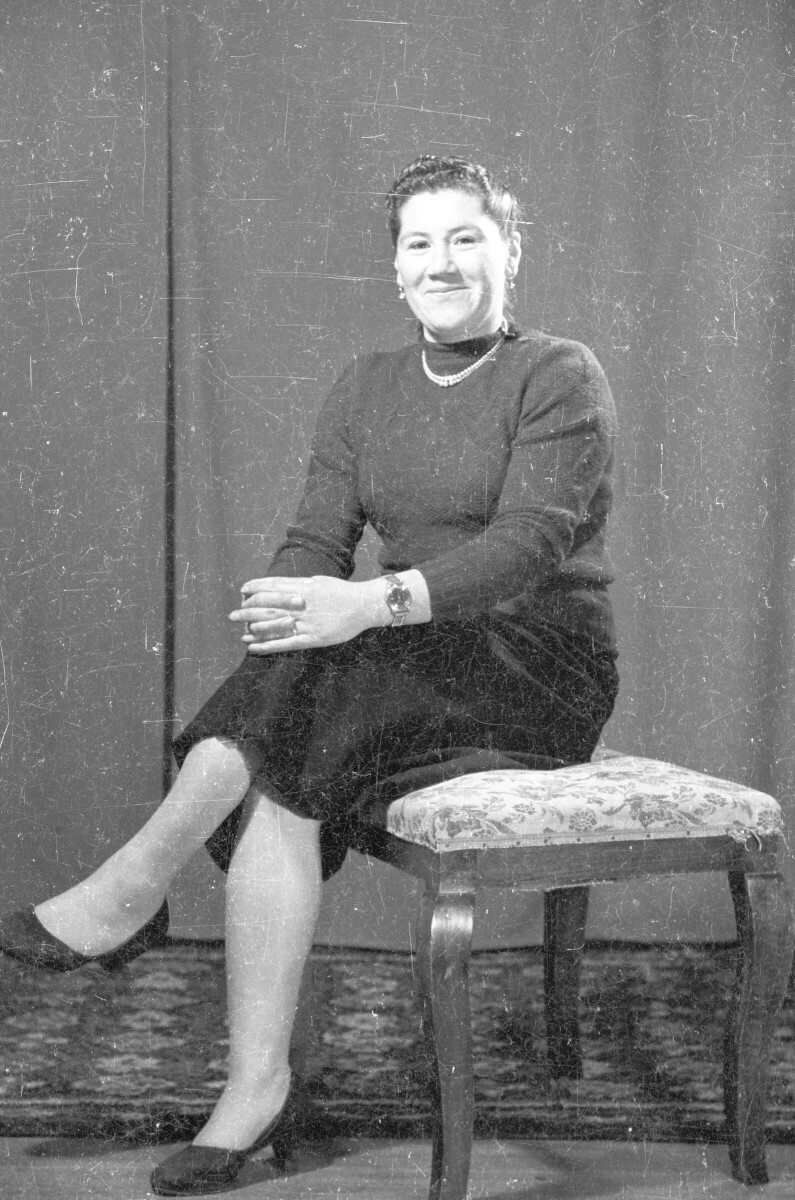 Retrato de estudio de Plano entero de Mujer con Vestido sentada de Medio perfil con las piernas cruzadas, sonriendo de frente