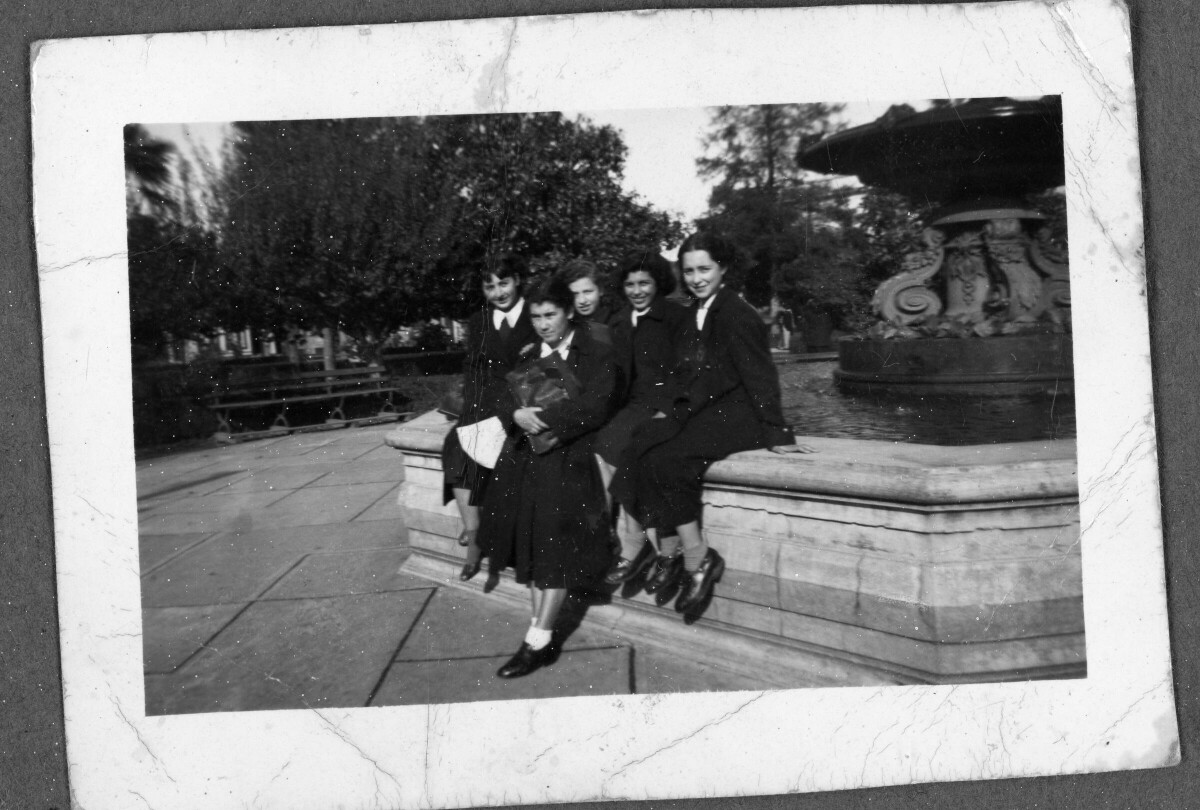 Retrato grupal de Plano General de cinco mujeres en la Pileta de la Plaza de la Concordia. Cuatro de ellas están sentadas en el borde de ésta y una de ellas, de pie.