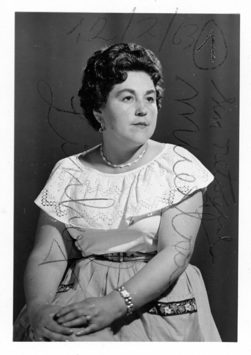 Retrato de estudio de Plano medio largo de una mujer posando sentada de Medio perfil. Tiene ambas manos apoyadas sobre su rodilla