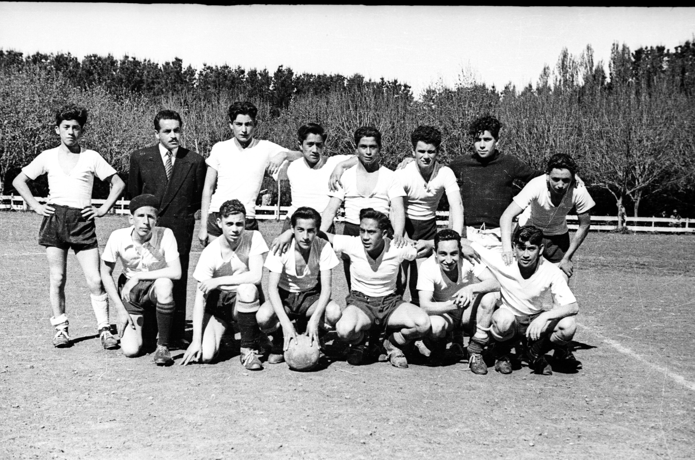 Retrato grupal de plano entero del Club deportivo Centenario formado junto a su director técnico en el interior de una cancha
