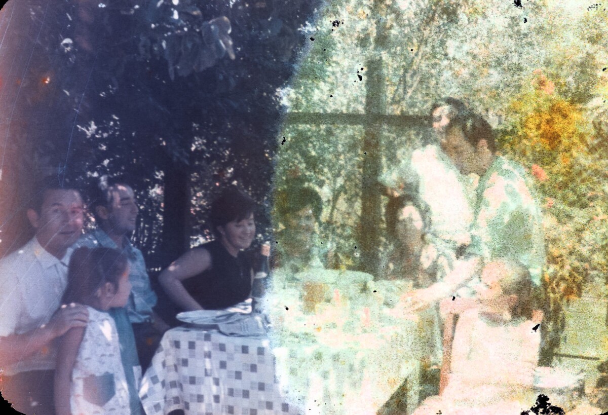 Plano americano de un grupo de Mujeres, Hombres y niñas sentados alrededor de una mesa servida en el patio de un lugar no identificado