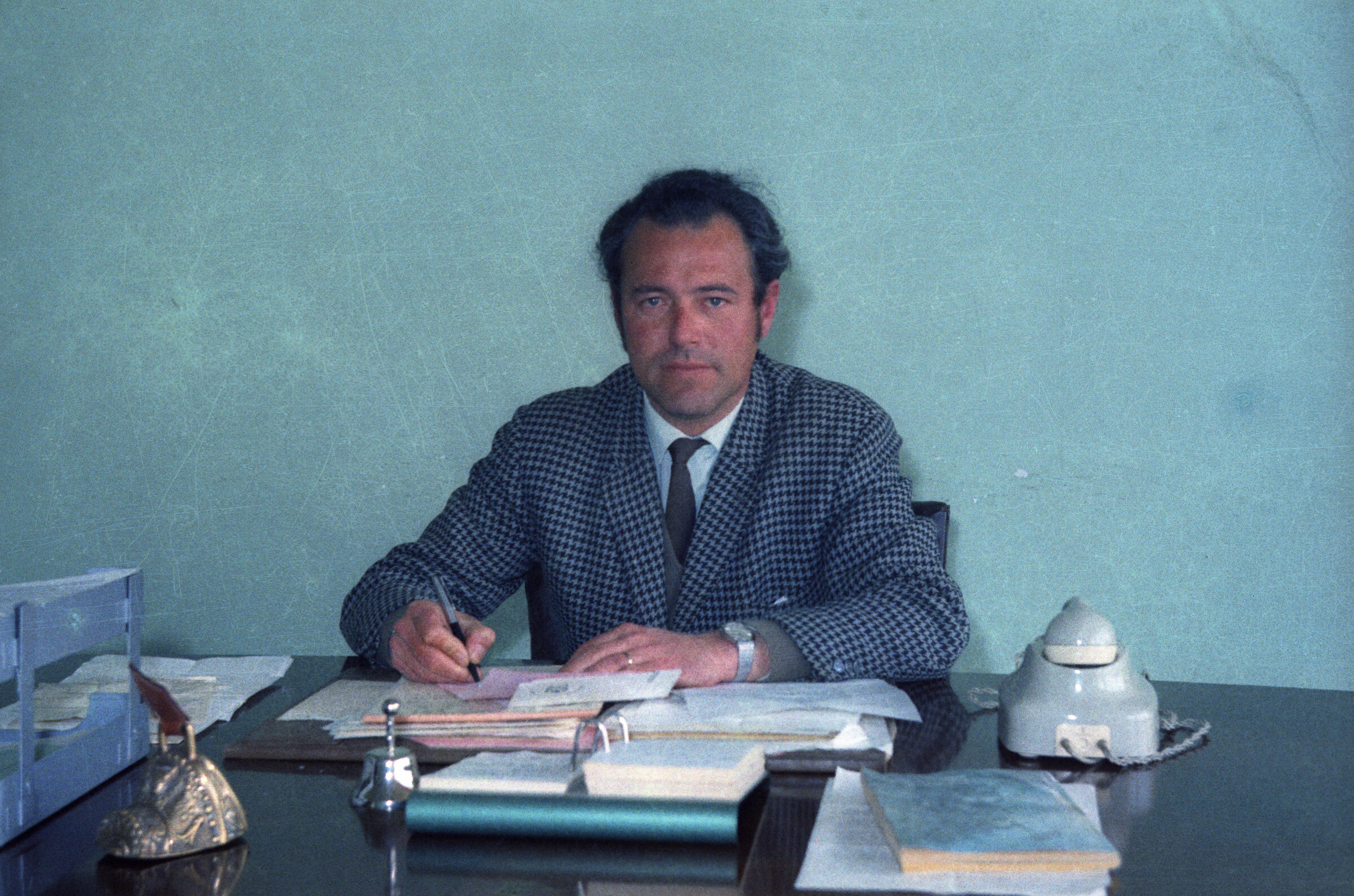 Plano medio de Enrique Larre sentado en un escritorio realizando anotaciones