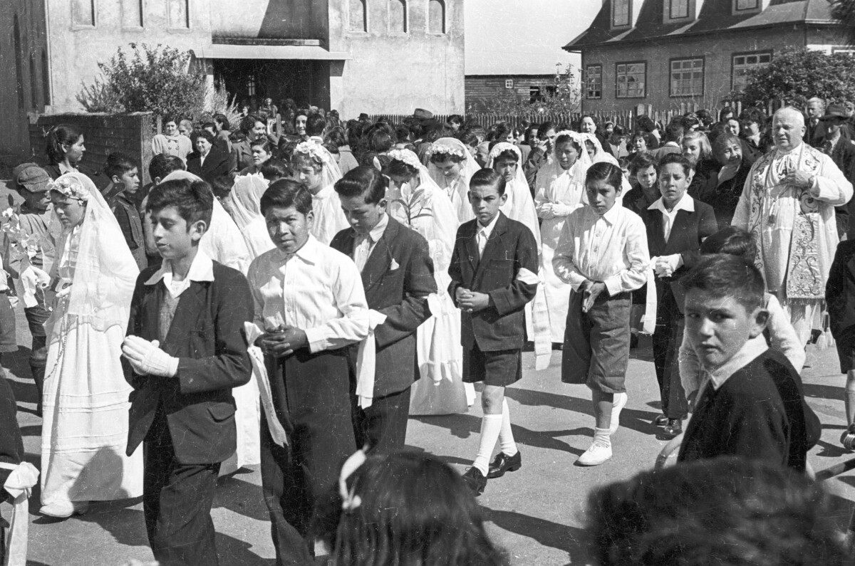 plano general de un grupos de Niñas y Niños formados en dos hileras. En el fondo un sacerdote está parado esperando que salgan todos de la parroquia inmaculada concepción.